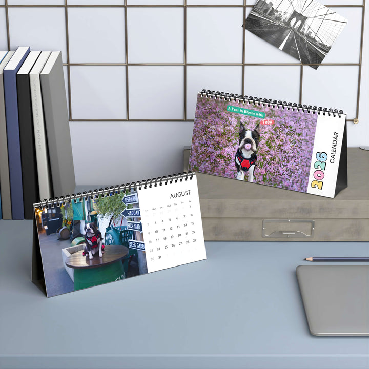 Two desk calendars on a surface with a tiled wall background