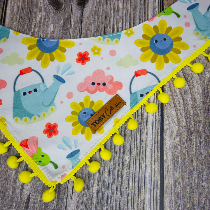 Colorful children's bib with cartoon characters and pom-pom trim on a wooden surface