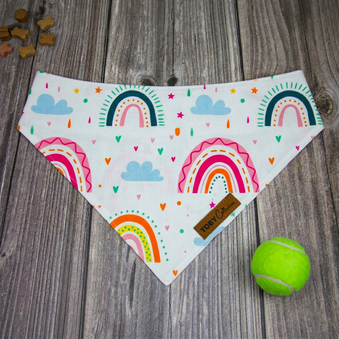 Colorful rainbow-patterned bandana on a wooden surface with a tennis ball.