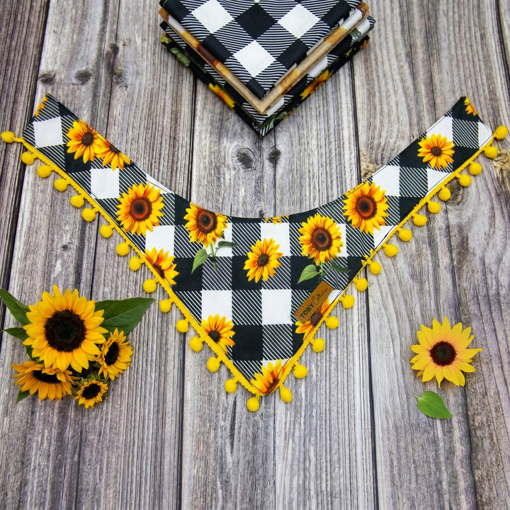 Plaid bandana with sunflowers and pom-poms on a wooden surface