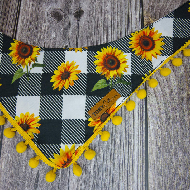 Plaid headband with sunflower patterns and yellow pom-poms on a wooden surface