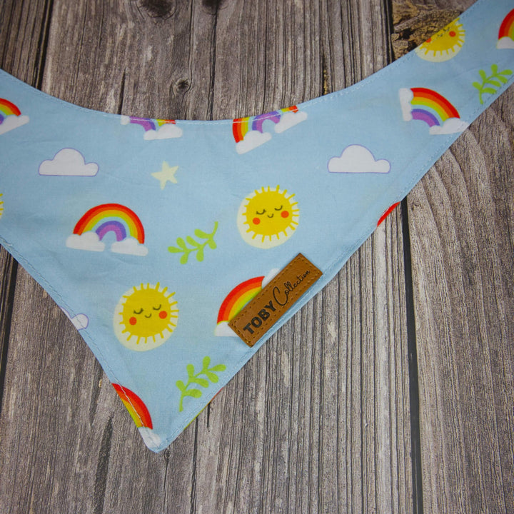 Fabric strip with rainbow, cloud, and sun patterns on a wooden surface