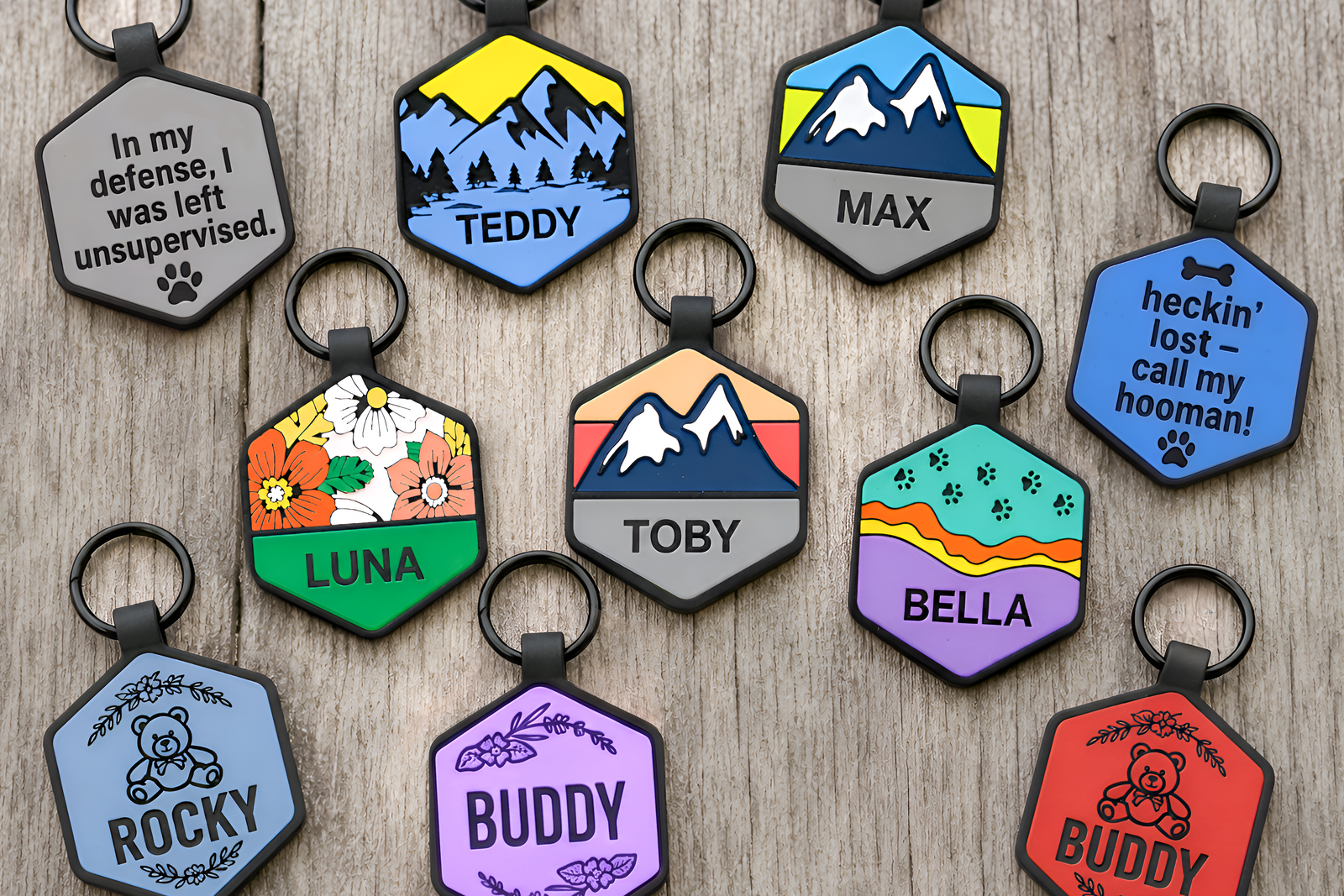 Collection of colorful pet tags with various designs and text on a wooden surface