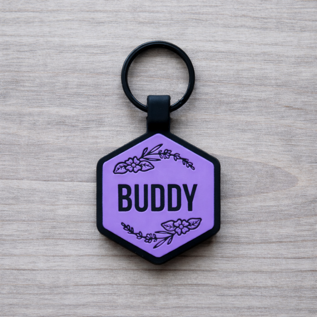Hexagonal purple pet tag with 'Buddy' and floral designs on a wooden surface