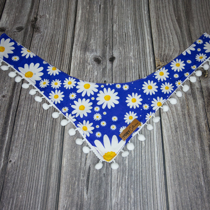 Toby Collection daisy print dog bandana on a rustic wooden base.