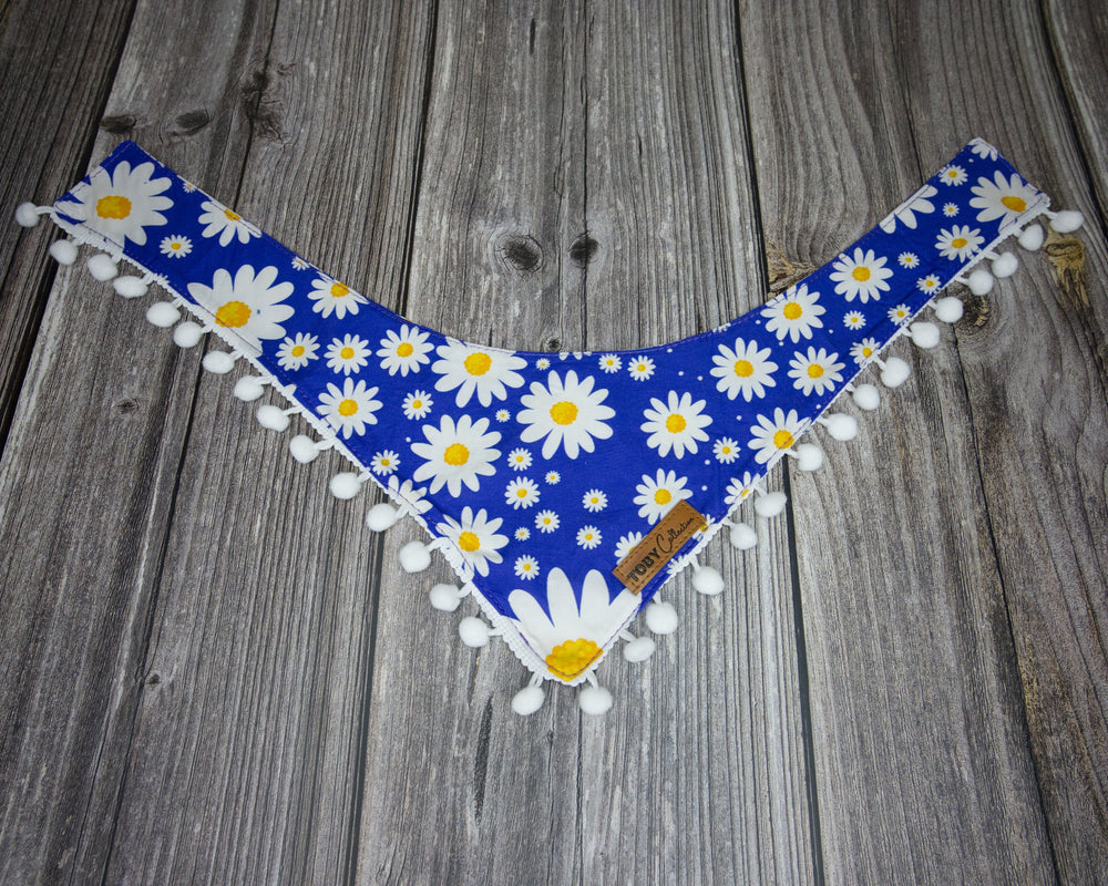 Toby Collection daisy print dog bandana on a rustic wooden base.