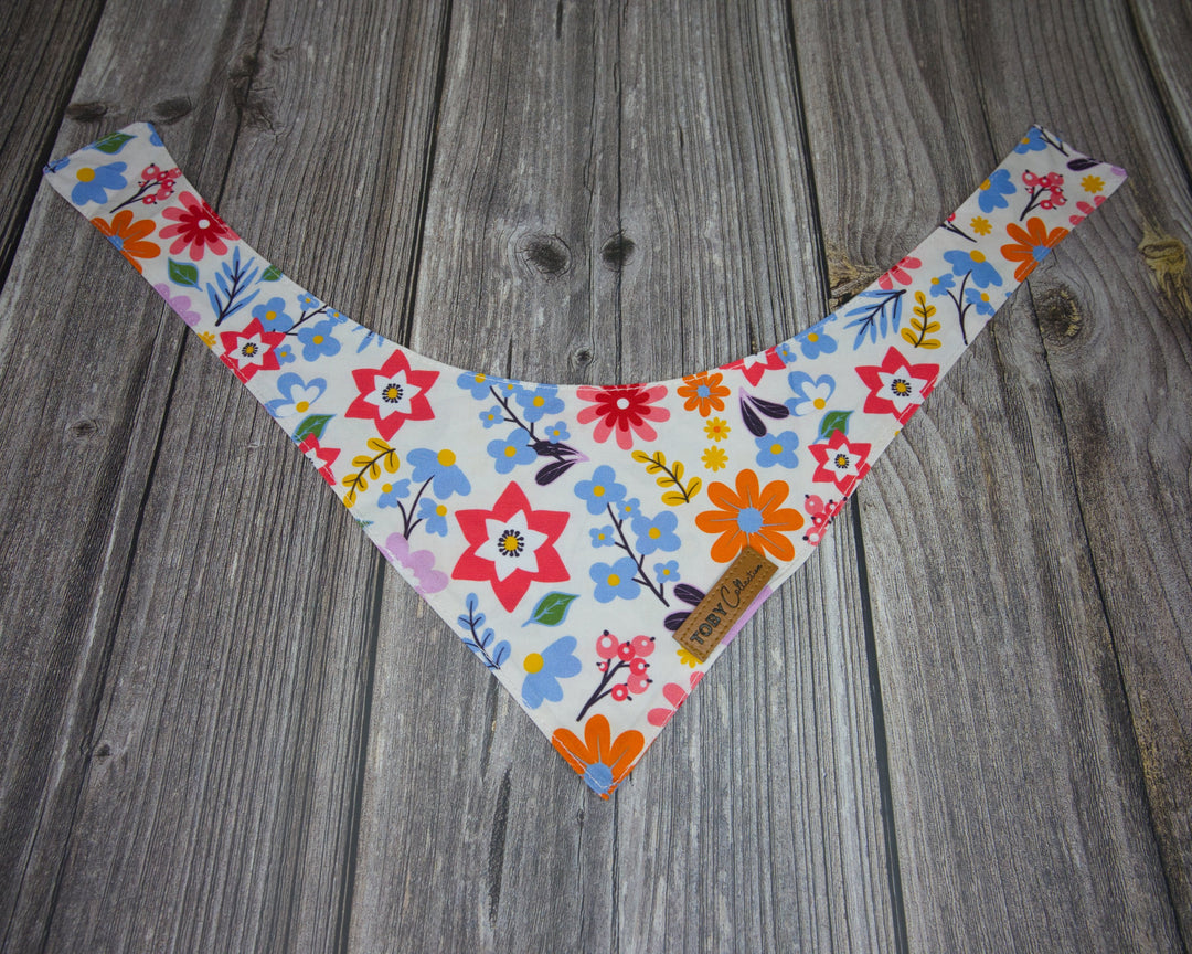 Toby Collection flowers print dog bandana on a rustic wooden base.