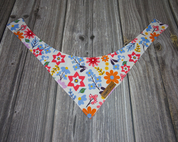 Toby Collection flowers print dog bandana on a rustic wooden base.
