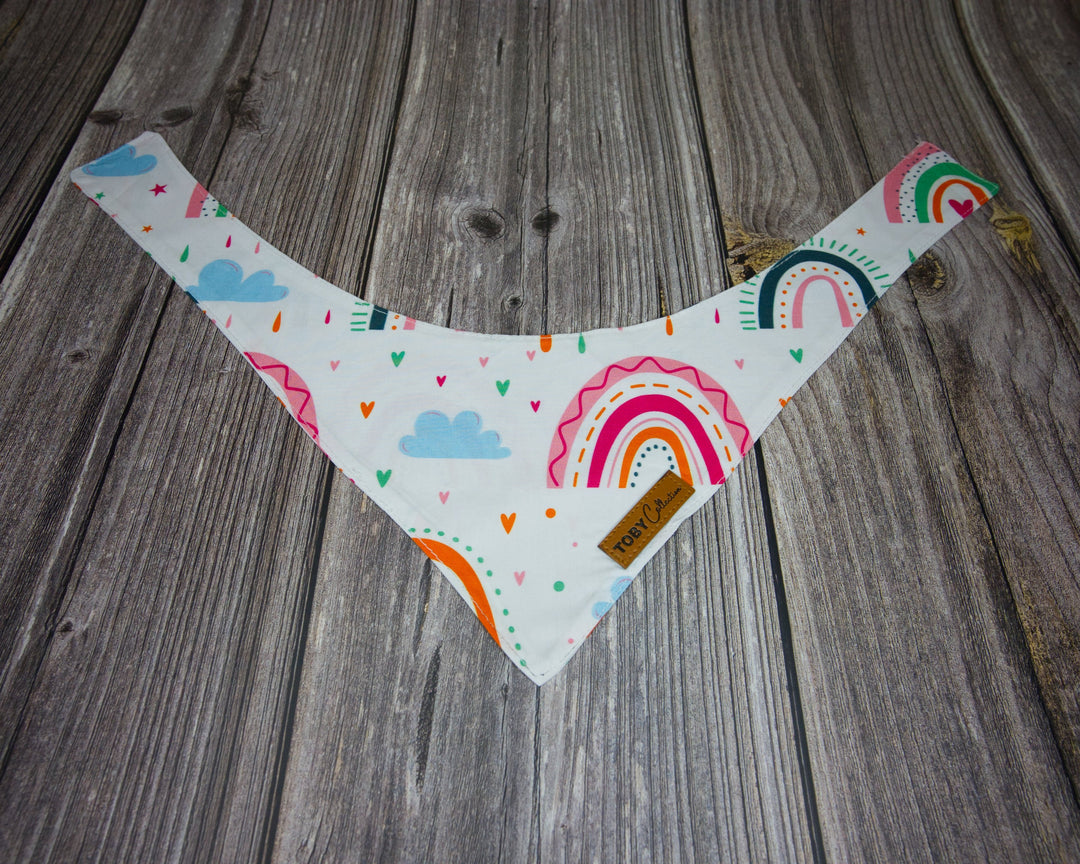 Toby Collection pink rainbow dog bandana on a rustic wooden base.
