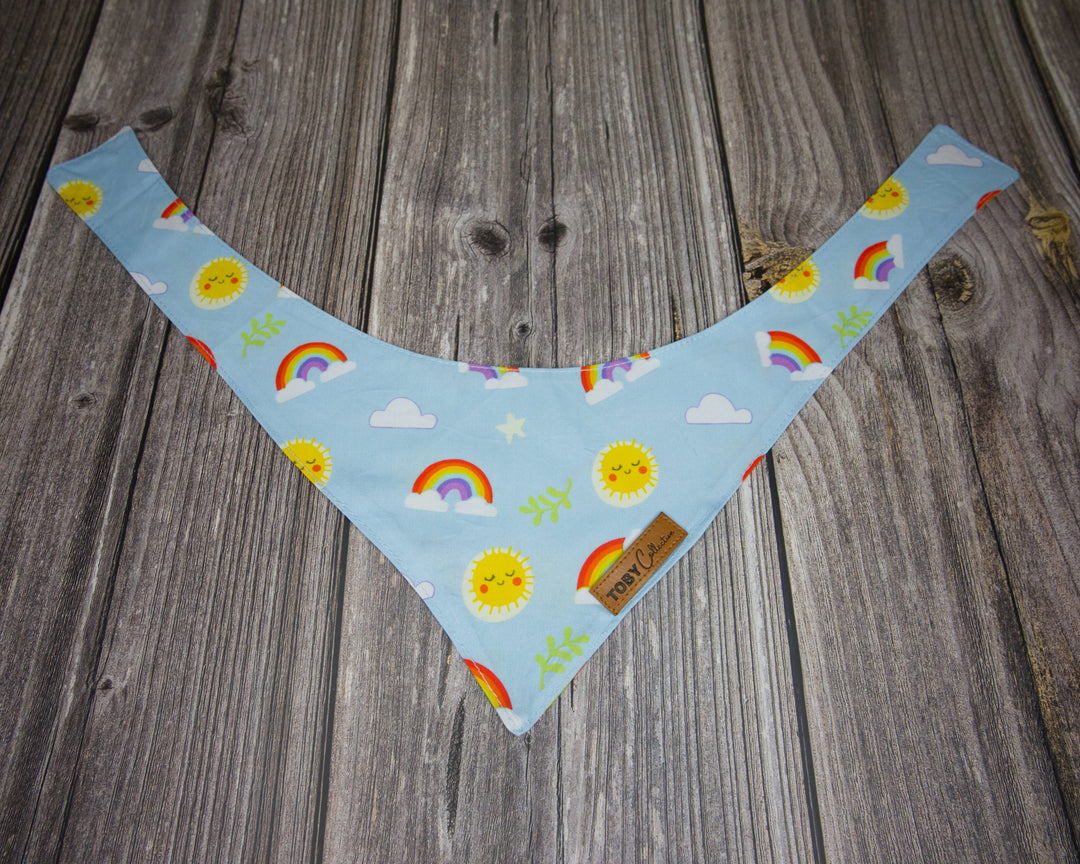 Toby Collection rainbow print dog bandana on a rustic wooden base.