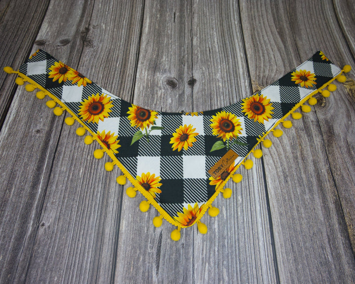 Toby Collection sunflower print dog bandana on a rustic wooden base.