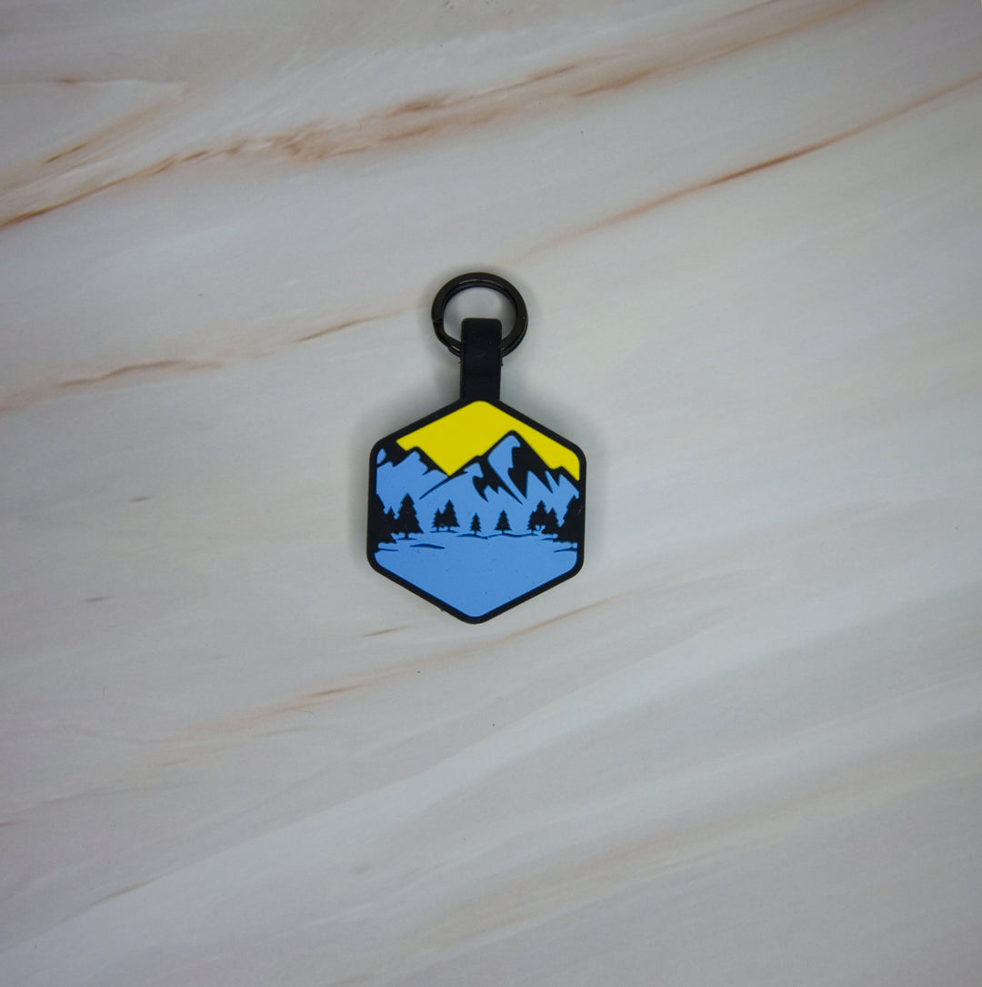 A personalized Toby Collection hexagonal dog tag with a blue and yellow mountain design 