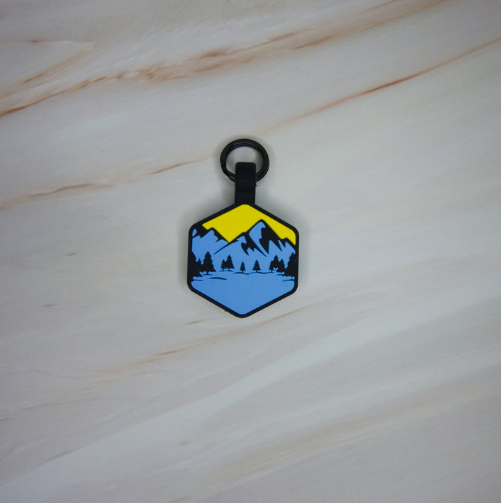 A personalized Toby Collection hexagonal dog tag with a blue and yellow mountain design 